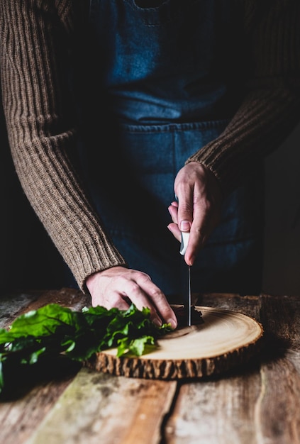 Ręce siekające zioła na drewnianej desce